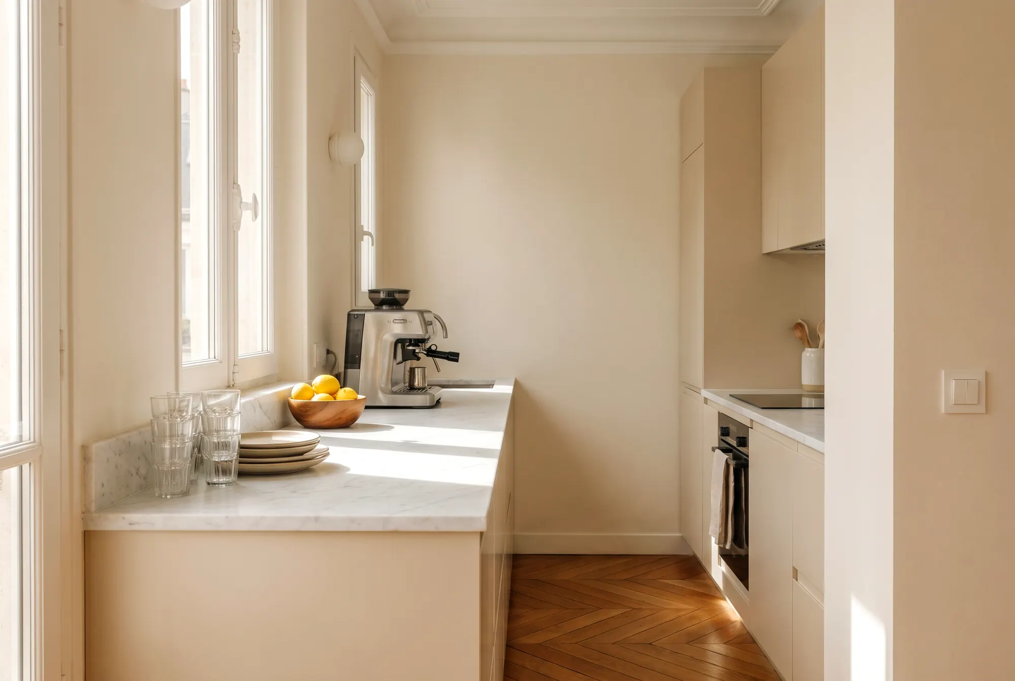 Cuisine ouverte nettoyée entre deux séjours, plan de travail en marbre dégagé, verres propres et bol de citrons