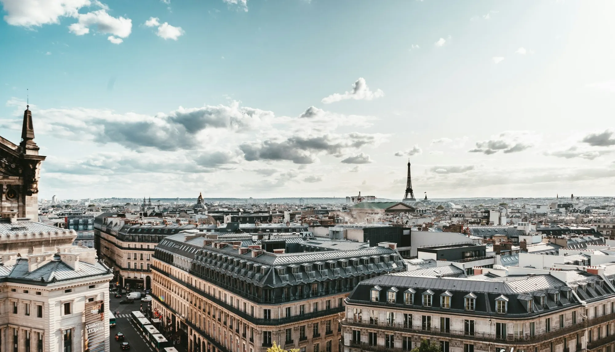 Toits de Paris et immeubles haussmanniens, la tour Eiffel à l’horizon sous un ciel clair