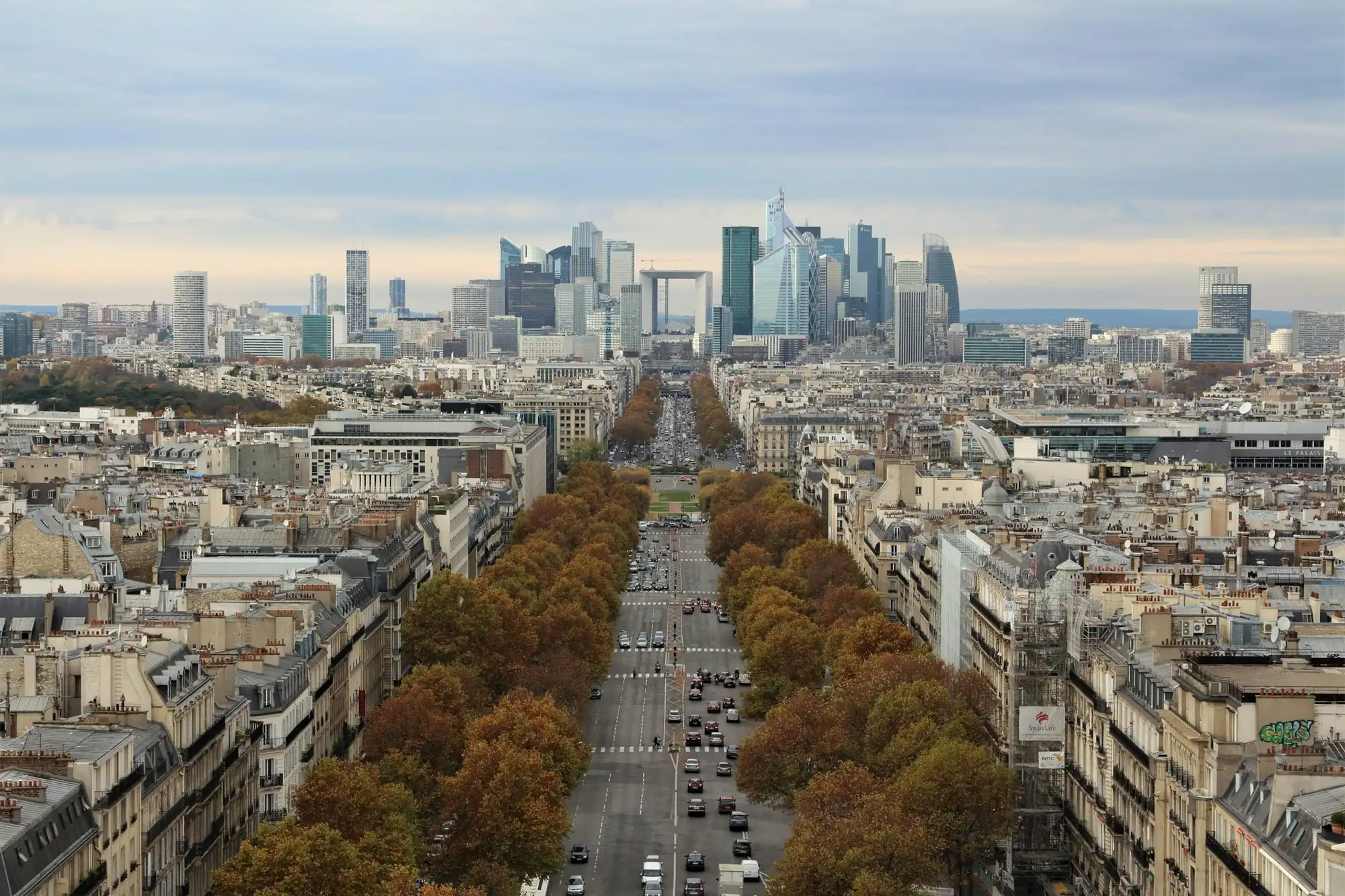 Avenue bordée d’arbres d’automne menant aux tours de La Défense