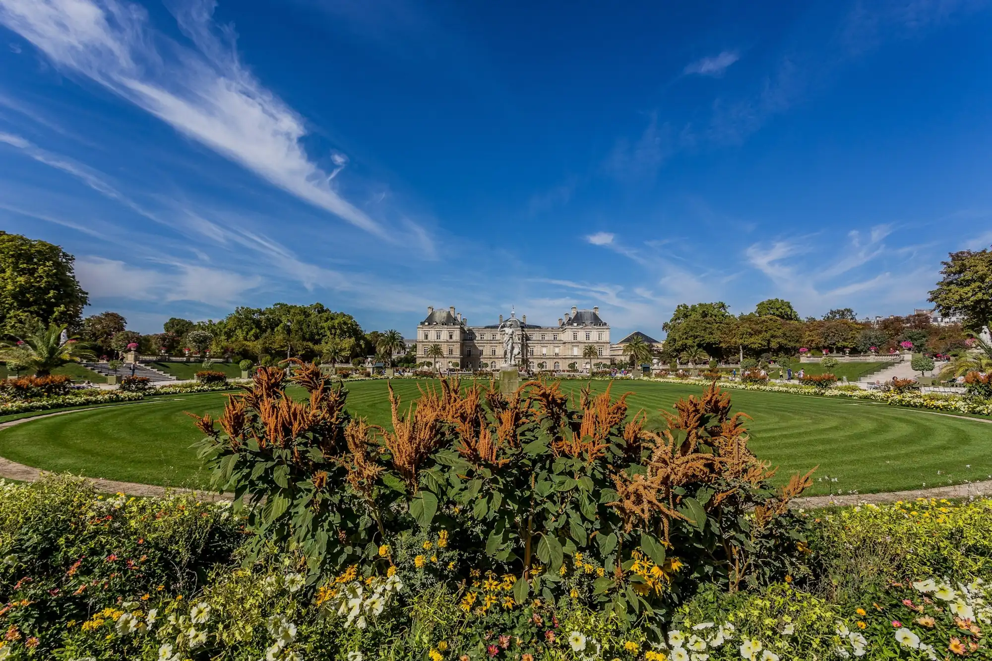 Jardin du Luxembourg fleuri devant le palais du Sénat, Paris 6e, sous un ciel bleu
