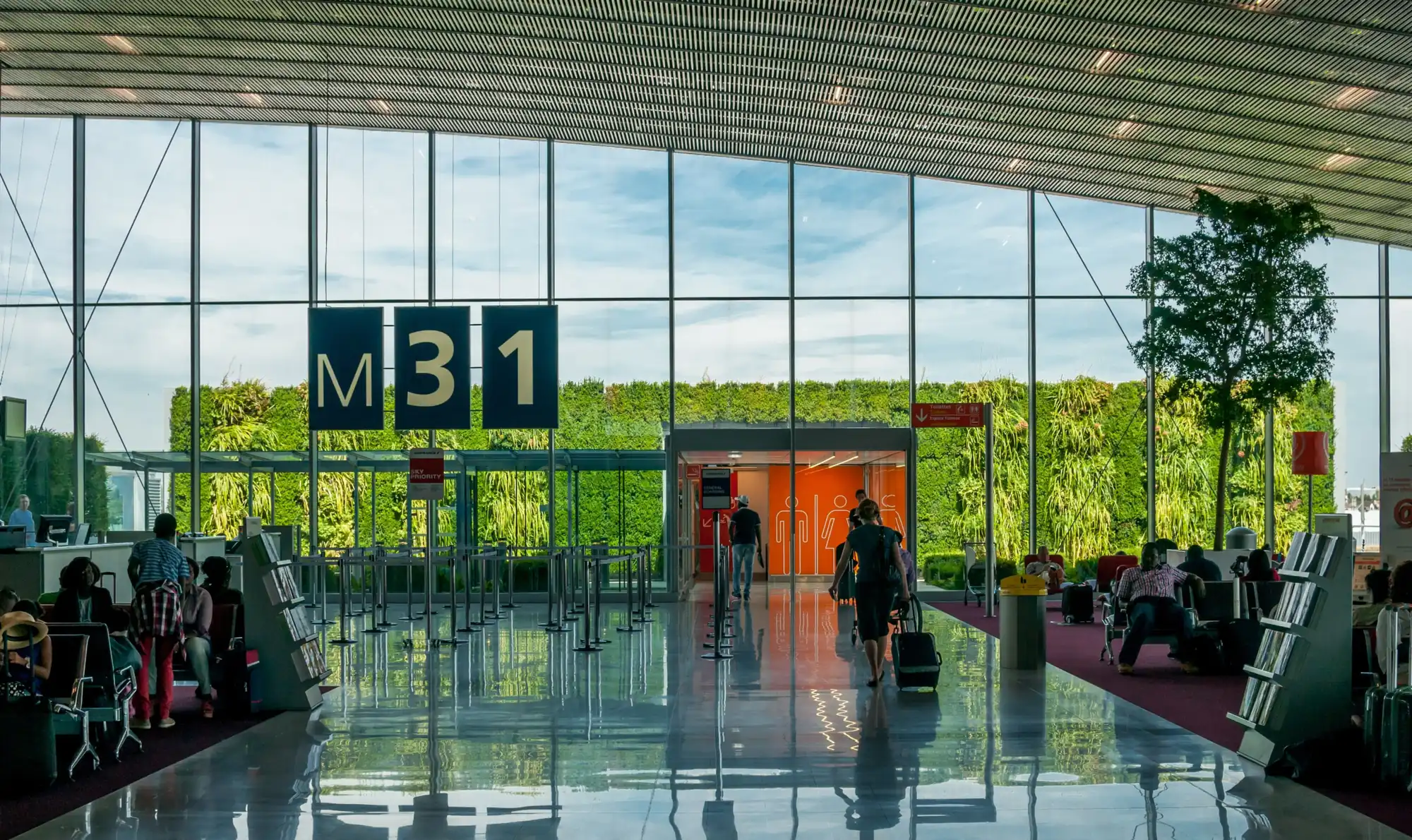 Hall vitré du terminal de l’aéroport Paris-Charles-de-Gaulle, mur végétal et voyageurs