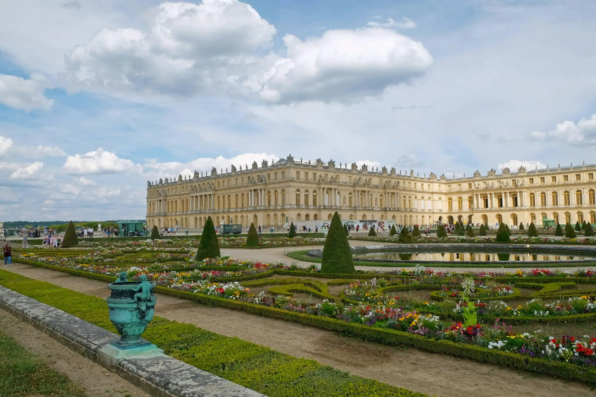 Château de Versailles et ses parterres fleuris sous un ciel bleu